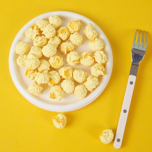 Detail of realistic PVC popcorn prop with puffed texture on a white ceramic plate