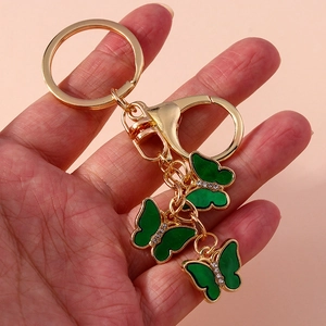Close-up of golden butterfly keychain with green enamel wings and shiny crystal rhinestones