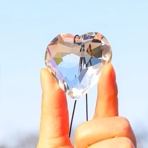 Faceted heart crystal suncatcher pendant reflecting sunlight against a clear blue sky