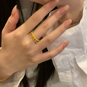 Golden bead tassel ring with hollow chain design worn by a model for a chic look