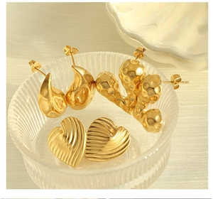 Close-up of gold titanium steel earrings with textured heart and water drop shapes