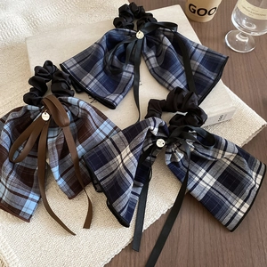 Detail of plaid bow scrunchies with long ribbons and golden metallic pendants
