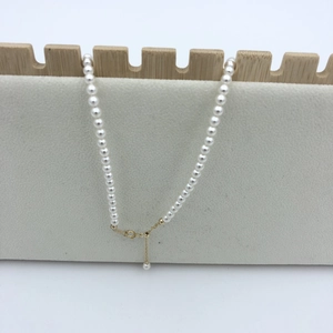 Macro detail of round pearl necklace with 14k gold-filled lobster clasp and extension chain
