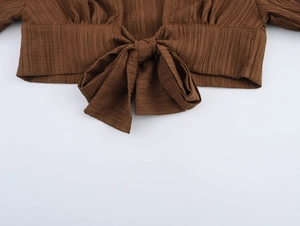 Detail of dark brown knot tie-front top with vertical pleated texture and bow design