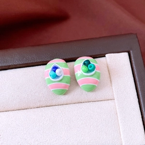 Close-up of luxury oval earrings with green and pink stripes and crystal accents
