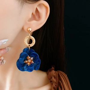 Detail of vintage blue flower earrings with amber bead center on female model