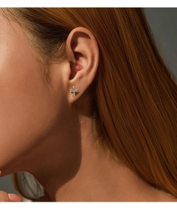Close-up of S925 silver cross earrings with moissanite stones on a female model