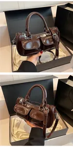 Detail of dark brown glossy cylinder handbag with dual front pockets and top handle