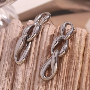 Detailed close-up of silver-tone chunky triple-link chain earrings on a wooden background