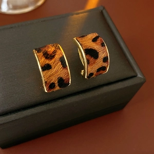 Détail des boucles d'oreilles léopard en forme de C avec bordure dorée sur coffret