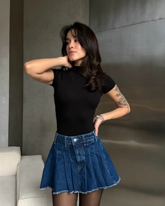 Dettaglio mini gonna di jeans plissettata vintage e crop top nero attillato