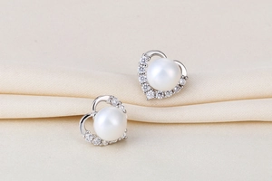 Macro shot of S925 silver heart earrings with white pearls and sparkling cubic zirconia