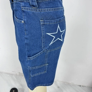 Dettaglio del ricamo a stella bianca sulla tasca posteriore dei pantaloncini di jeans blu