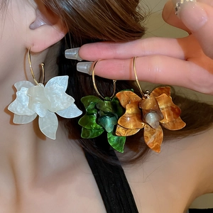 Close-up of three colors of vintage resin flower hoop earrings worn by a model