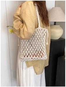 Detail of hand-woven hollow shoulder bag with bohemian tassels in creamy white