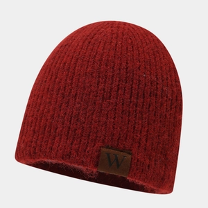 Detailed close-up of a red knit beanie featuring a brown leather W-label and wool texture