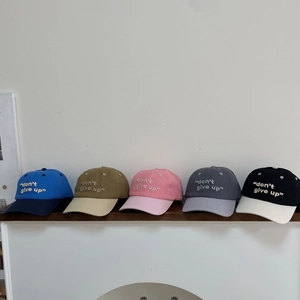 Detalle de cinco gorras de béisbol de algodón de colores con bordado Don't Give Up