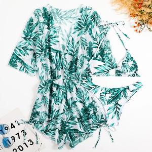 Flat lay of a three-piece tropical palm leaf print bikini set with a matching waist-tie cover-up