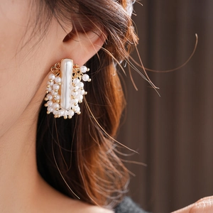 Détail du clou d'oreille doré avec une grande perle rectangulaire et petites perles
