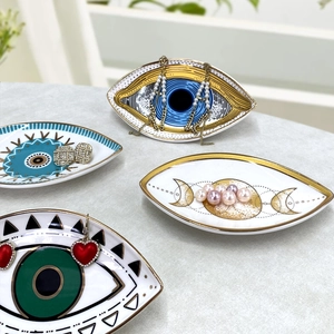 Detailed view of evil eye ceramic jewelry trays with gold trim on marble surface