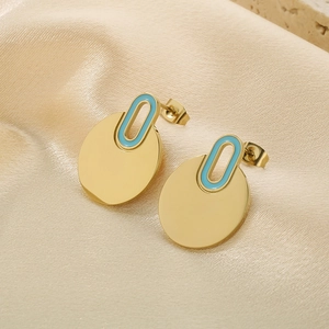 Detail of gold polished earrings with light blue enamel on elegant beige satin fabric
