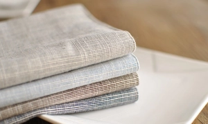 Macro shot of stacked linen napkins with fine checkered textures in multiple natural tones