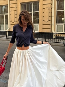 Dynamic street view of a high-waisted white pleated maxi skirt with a blue cardigan