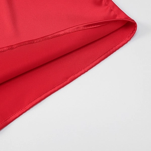 Close-up of red satin dress hem showing high-quality stitching and smooth fabric texture