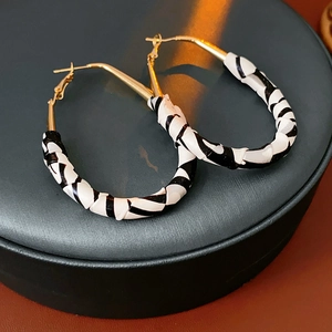 Détail de l'imprimé léopard en simili cuir sur des boucles d'oreilles créoles dorées
