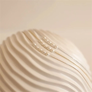 Close-up of gold and silver necklaces with elegant freshwater pearls on a textured background