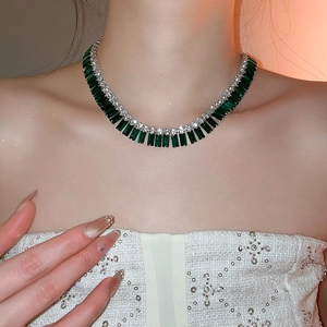 Close-up of baguette-cut emerald green necklace with sparkling crystals on female model