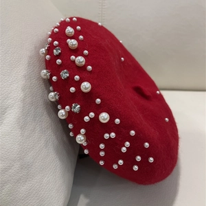 Detail of red wool beret featuring elegant white faux pearls and shiny silver rhinestones