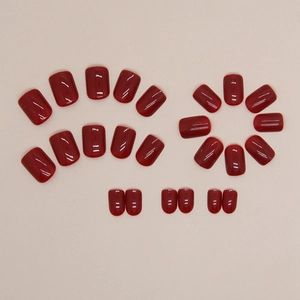 Glossy deep red square fake nails kit set on neutral background for festive manicure