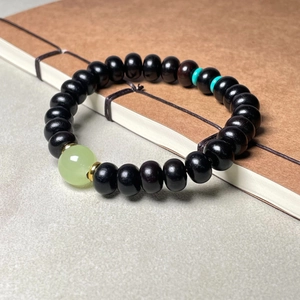 Bracelet en bois de santal vert et bois de poirier noir avec perle de jade sur carnet vintage