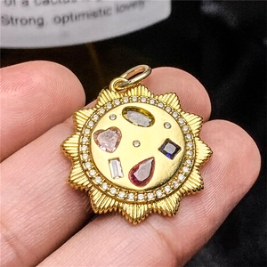 Detailed close-up of a gold sun-shaped pendant featuring multi-color gemstones and zircon