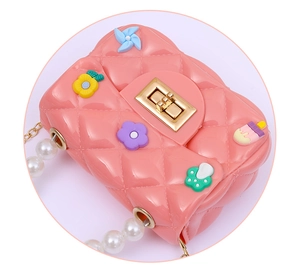 Detail of pink quilted mini jelly bag with pearl handle and colorful 3D cartoon charms