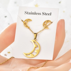 Détail d'une parure dorée en acier inoxydable avec pendentif lune et boucles d'oreilles