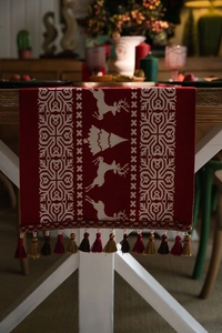 Macro detail of red Christmas table runner with white elk jacquard and colored tassels