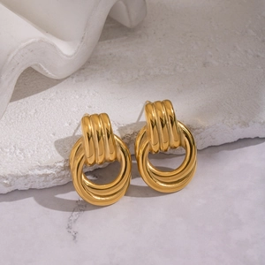 Minimalist geometric gold hoop earrings with textured ridges on a luxury stone background