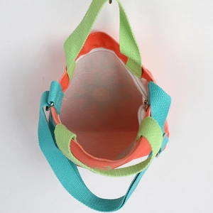 Kids orange canvas handbag with green handles and blue strap featuring a zipper closure
