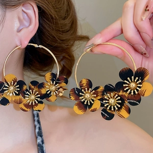 Macro detail of leopard print fabric flower hoop earrings with golden metallic accents