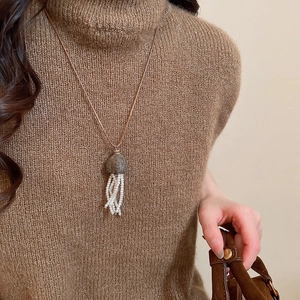 Detail of creative jellyfish pendant with small pearls on a brown turtleneck sweater