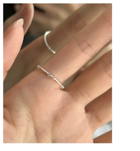 Macro shot of silver bow knot ring on finger showing twisted rope texture detail