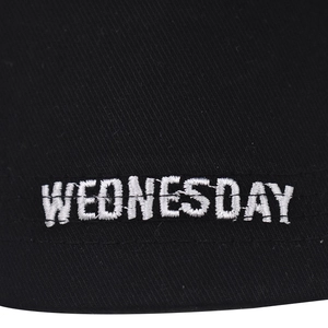 Gros plan sur la broderie blanche WEDNESDAY en relief sur la casquette noire