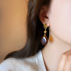 Boucles d'oreilles Maillard en résine ambre vintage avec détails dorés sur un modèle