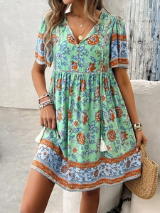 Detail of bohemian floral mini dress featuring V-neckline with tassel ties and buttons