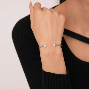 Close-up of minimalist geometric open bangle with two sparkling zircon stones on a wrist