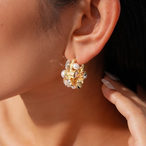 Macro shot of gold floral earrings with pearls and crystals on female model