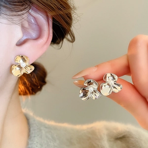 Macro detail of floral earrings with pearl center and hand-hammered metal texture