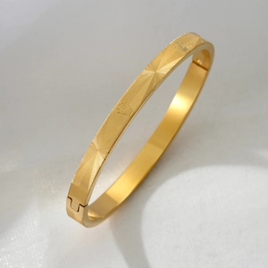 Titanium steel bangle with golden sunburst radial pattern and secure buckle closure